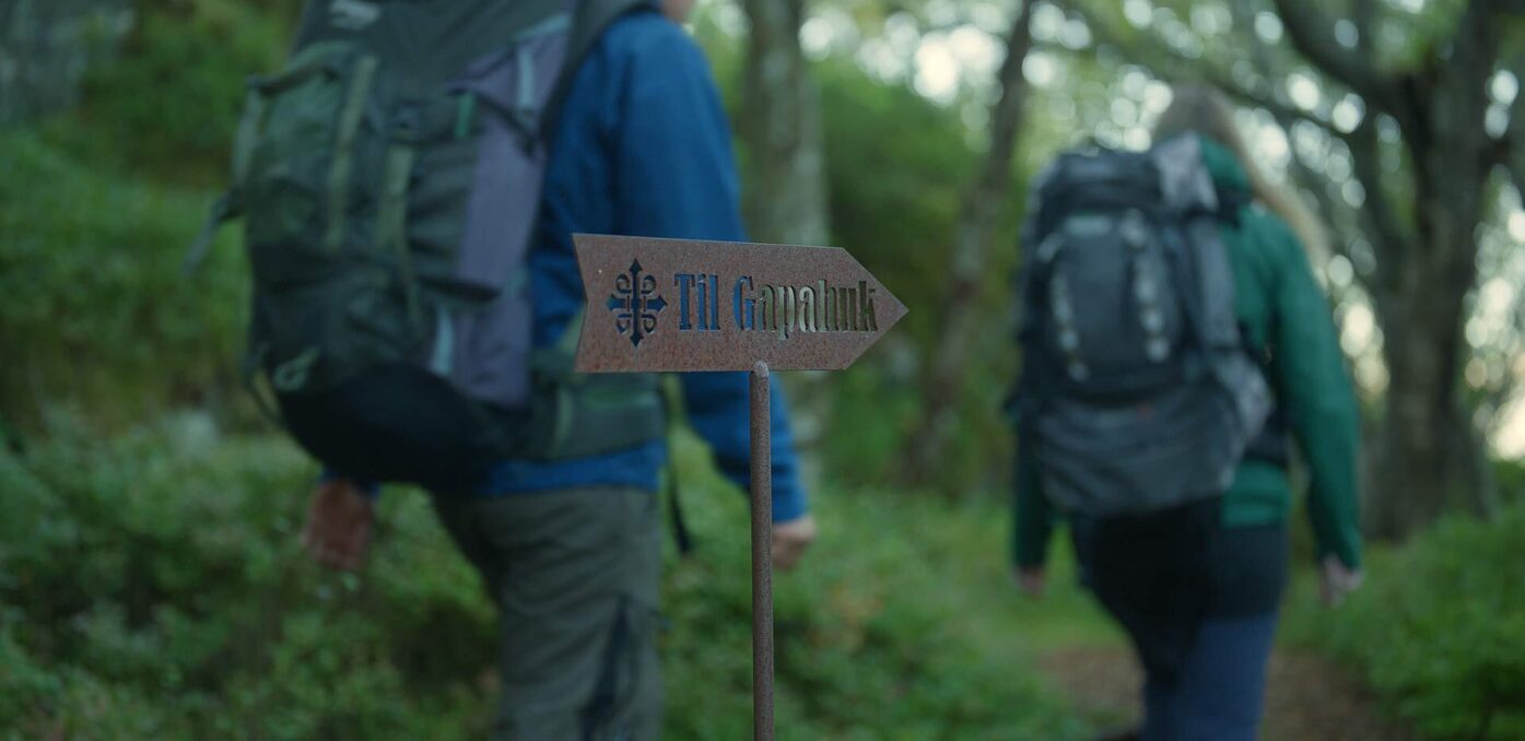 Folk på tur passerer et skilt med teksten "Gapahuk". Foto