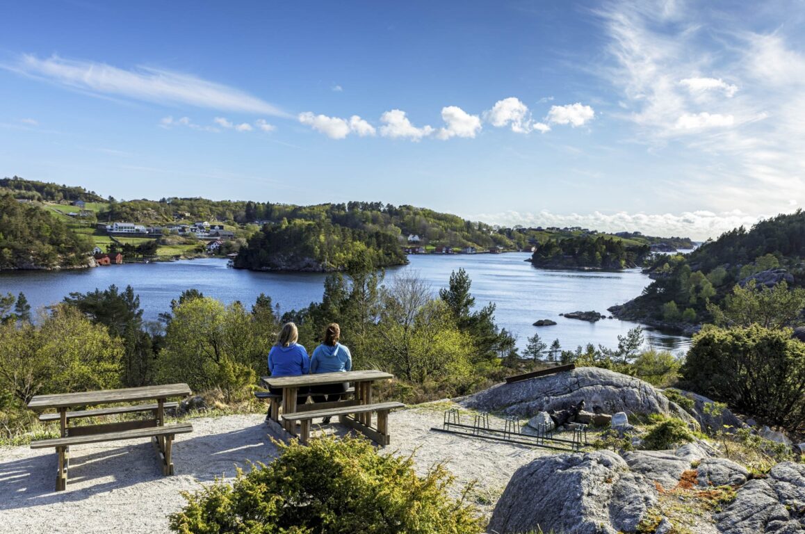 Two people are sitting at a rest area, looking out over the sea